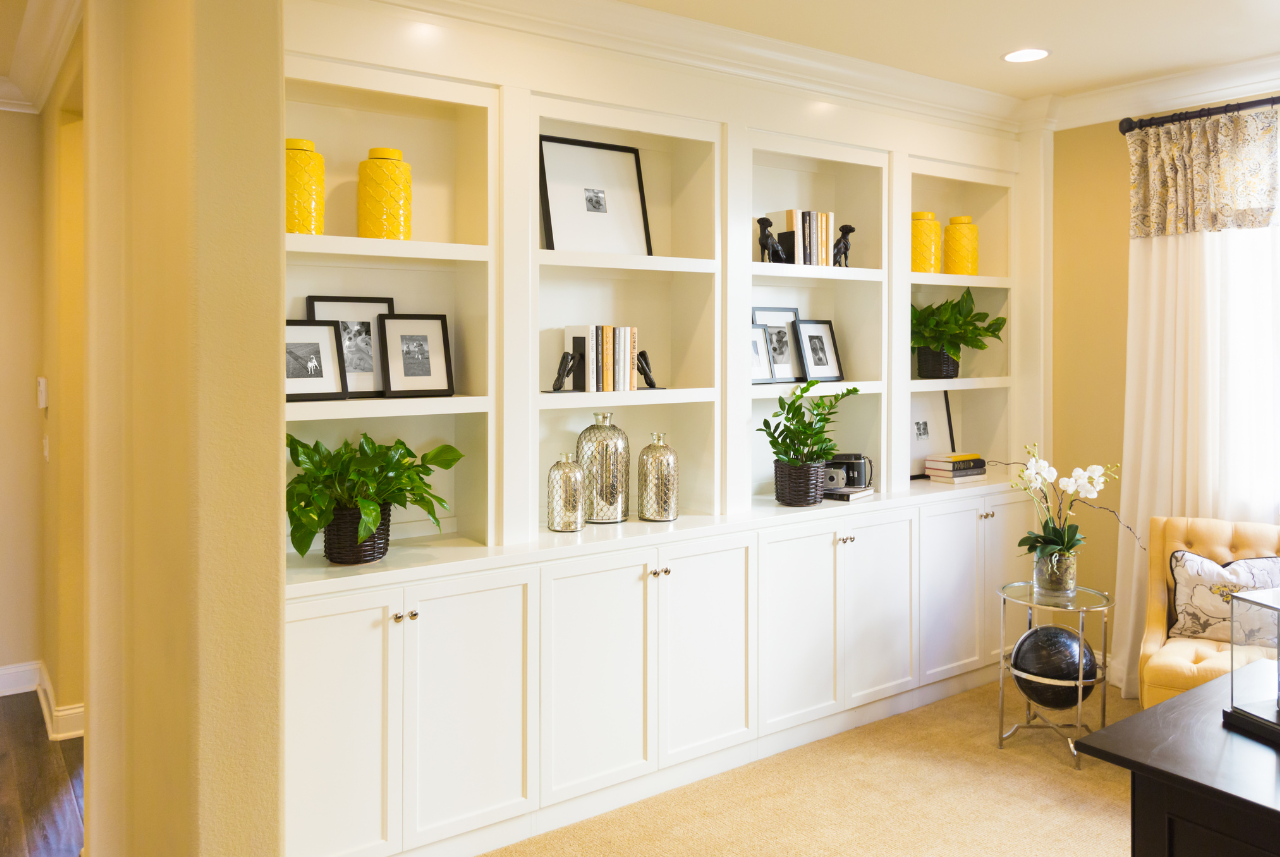Custom cabinets Milwaukee - Elegant living room with built-in white shelving units displaying decorative items and framed photos.