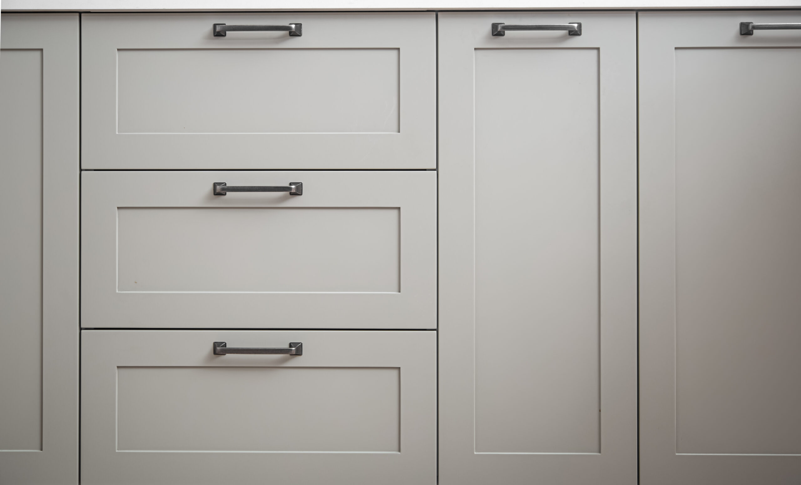 White kitchen cabinets with metal pulls or knobs on the doors.